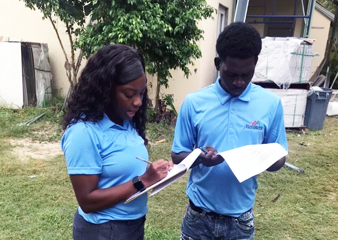Two MicroAntix team members in blue polos reviewing project documentation on site.